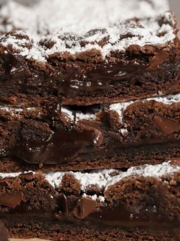 Stacked of three chocolate cookie bars topped with powdered sugar.