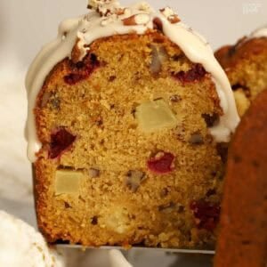 Closeup of a slice of pumpkin bundt cake filled with apples, cranberries, and pecans.