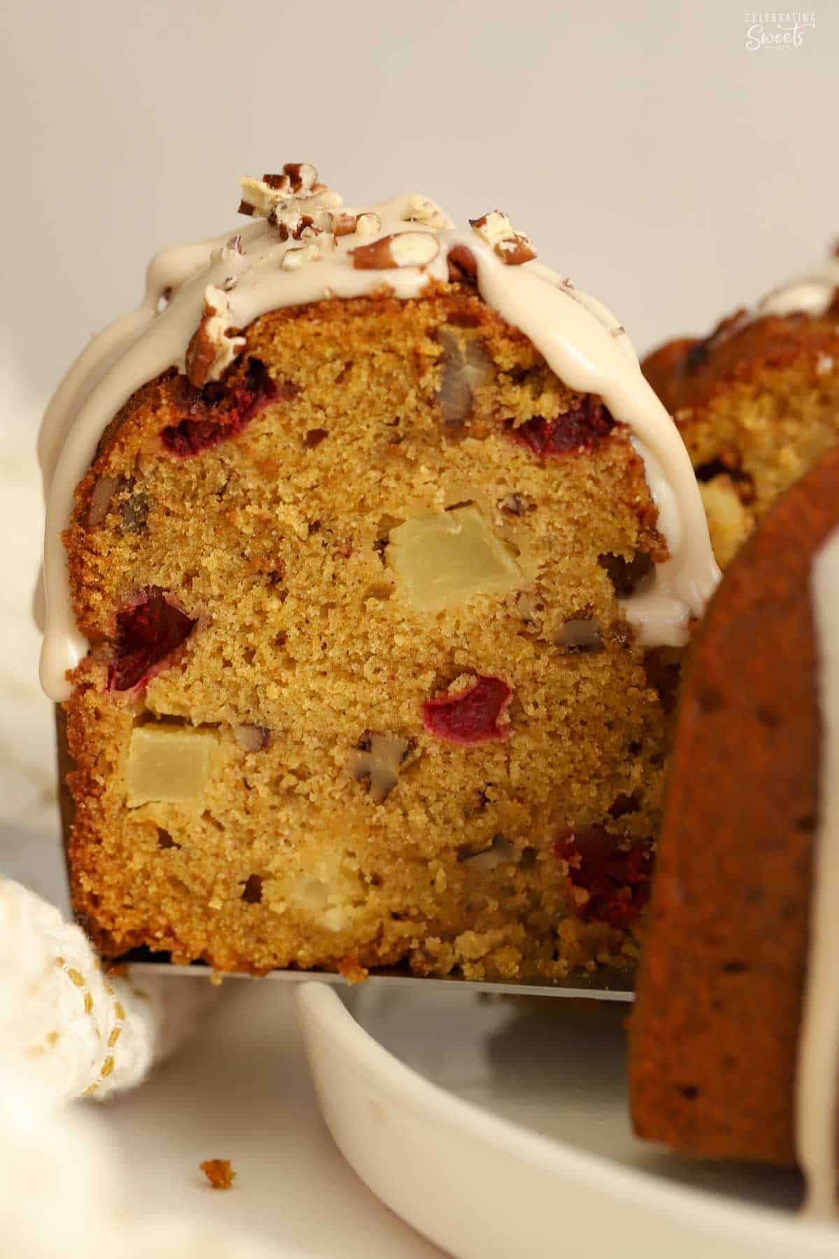 Closeup of a slice of pumpkin bundt cake filled with apples, cranberries, and pecans.