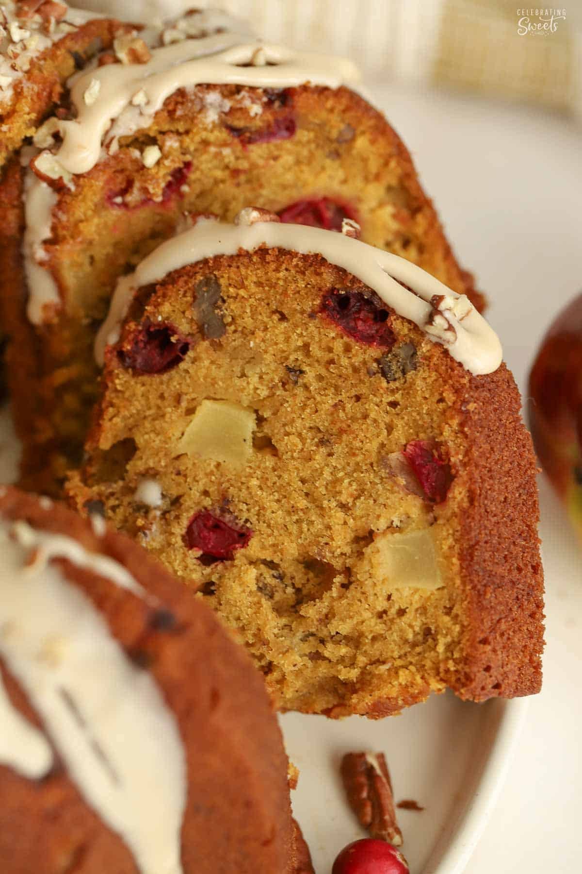 Slices of of pumpkin bundt cake filled with apples, cranberries, and pecans laying on each other.