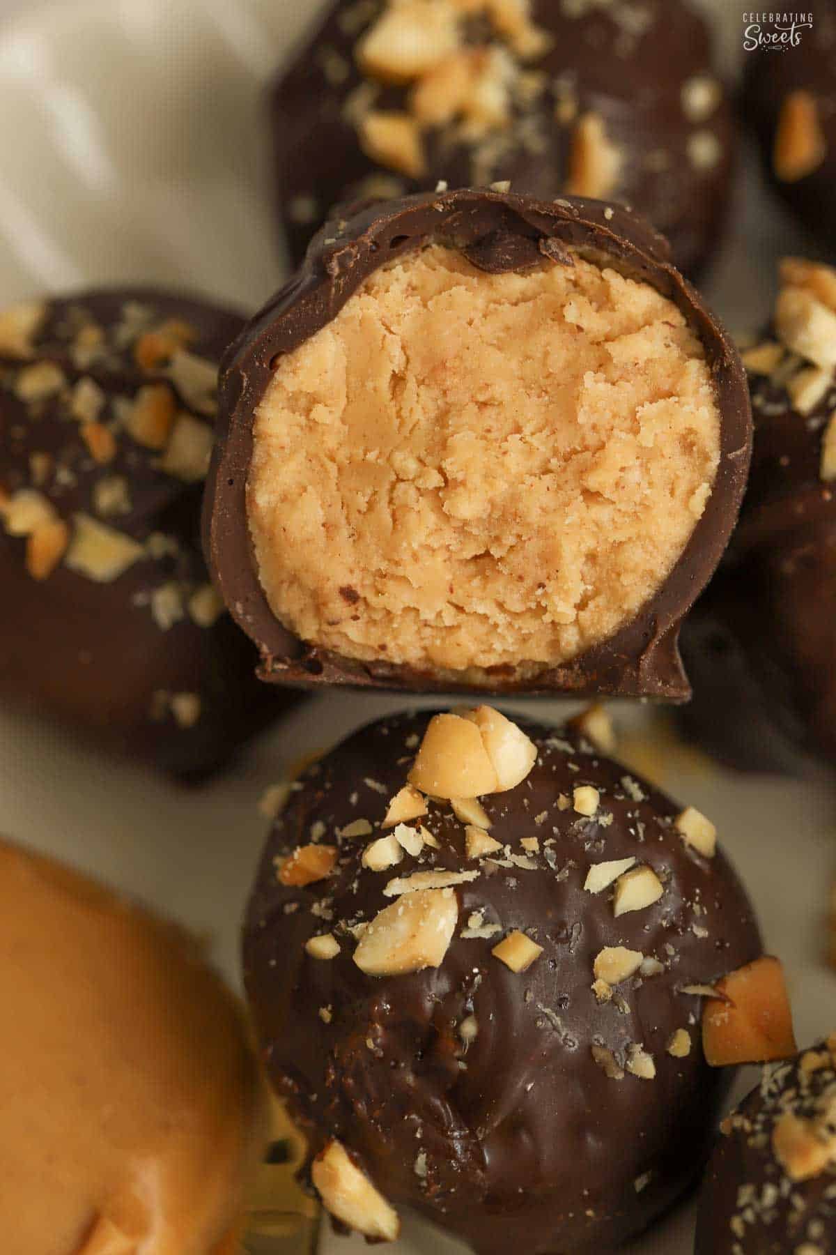Half of a chocolate covered peanut butter ball topped with chopped peanuts.