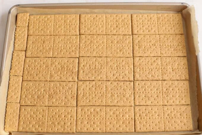 Graham crackers laid out on a parchment-lined baking sheet.