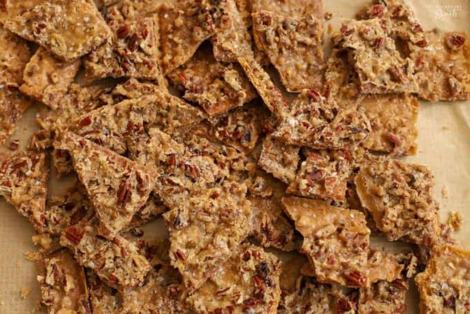 Pieces of pecan praline toffee on a parchment-lined baking sheet.