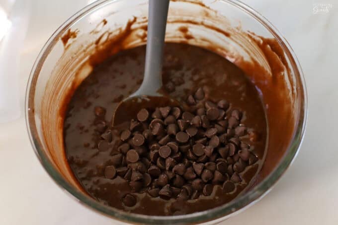 Brownie batter and chocolate chips in a glass bowl.