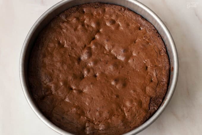 Baked brownie in a round metal cake pan.