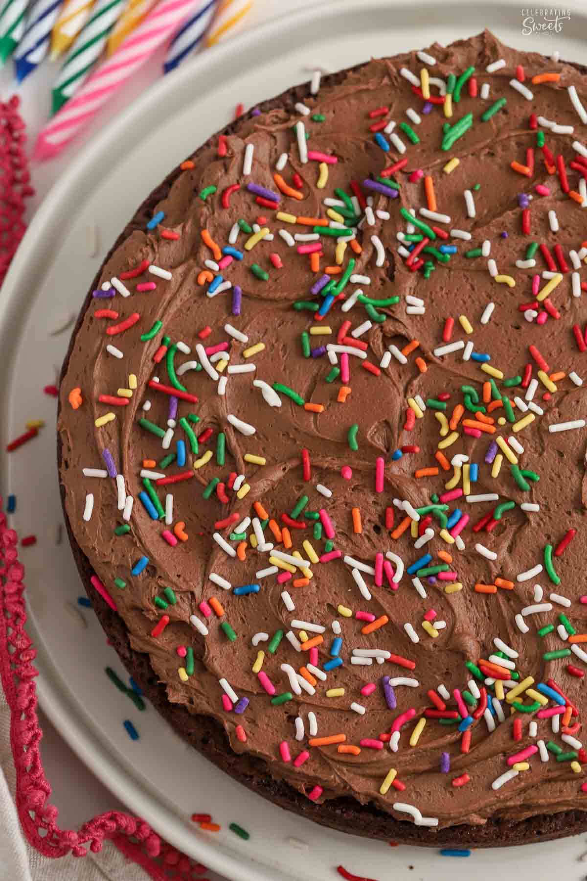 Overhead view of a brownie cake topped with chocolate frosting and rainbow sprinkles.