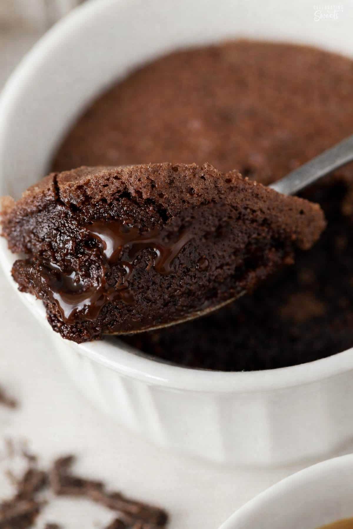 Brownie pudding on a spoon sitting on a ramekin.