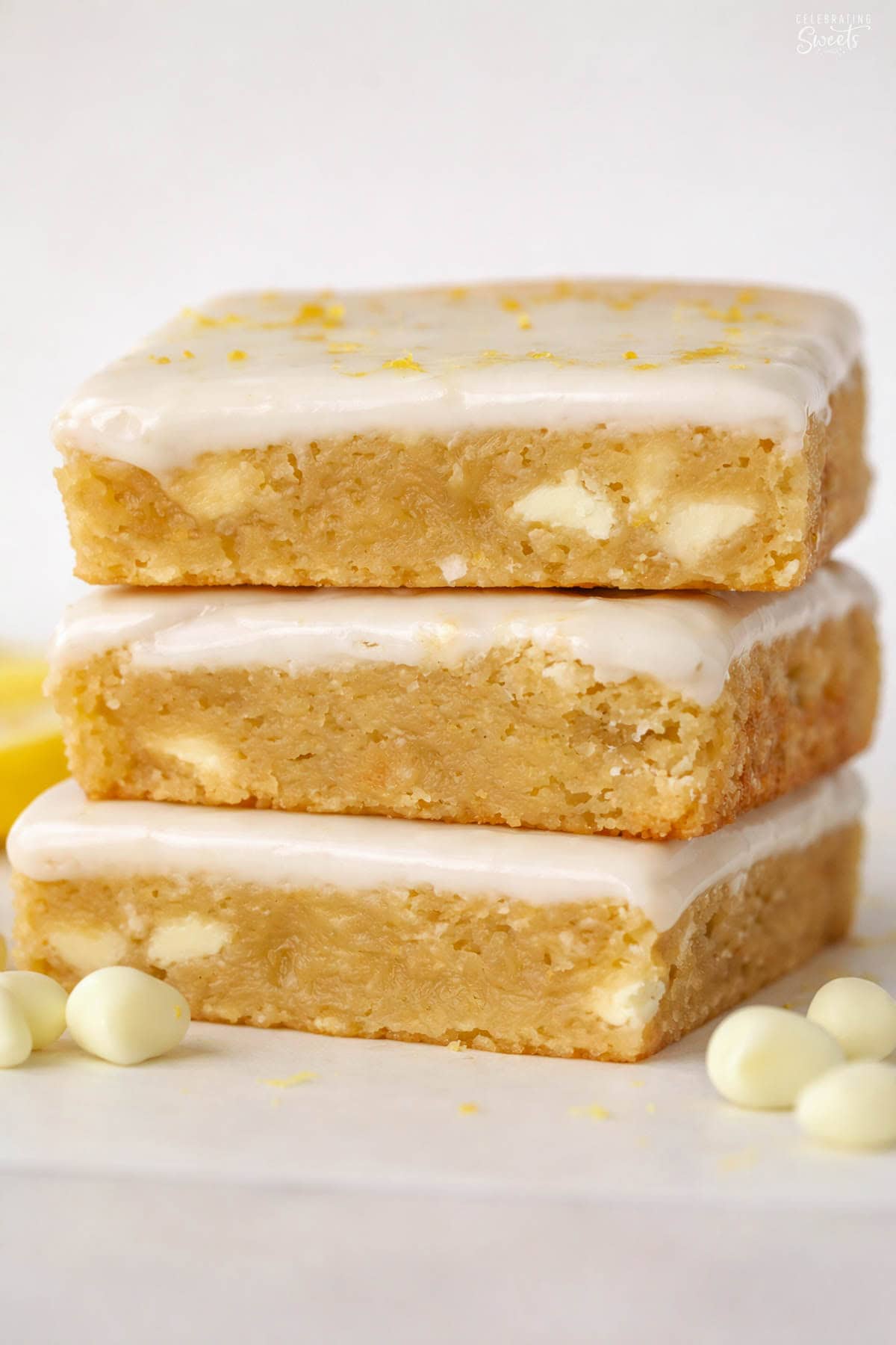 Stack of three lemon brownies topped with white icing and lemon zest.