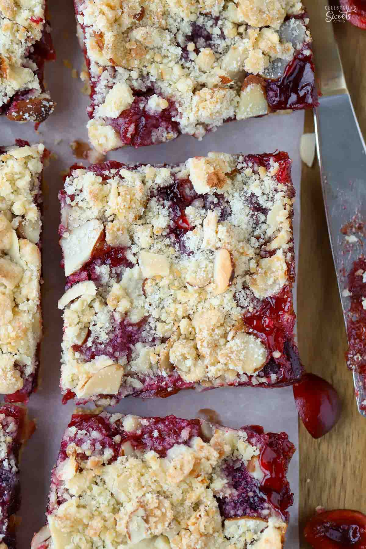 Almond cherry crumble bars on a piece of parchment paper.