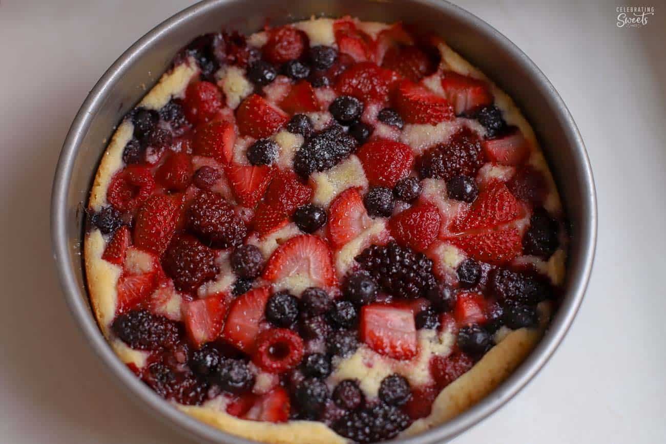 Lemon cake topped with mixed berries in a round metal cake pan.