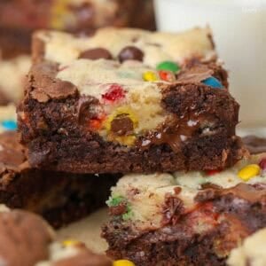 M&M brookie bars stacked on a piece of parchment paper.