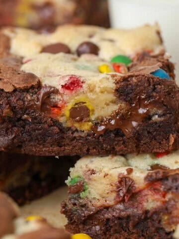 M&M brookie bars stacked on a piece of parchment paper.