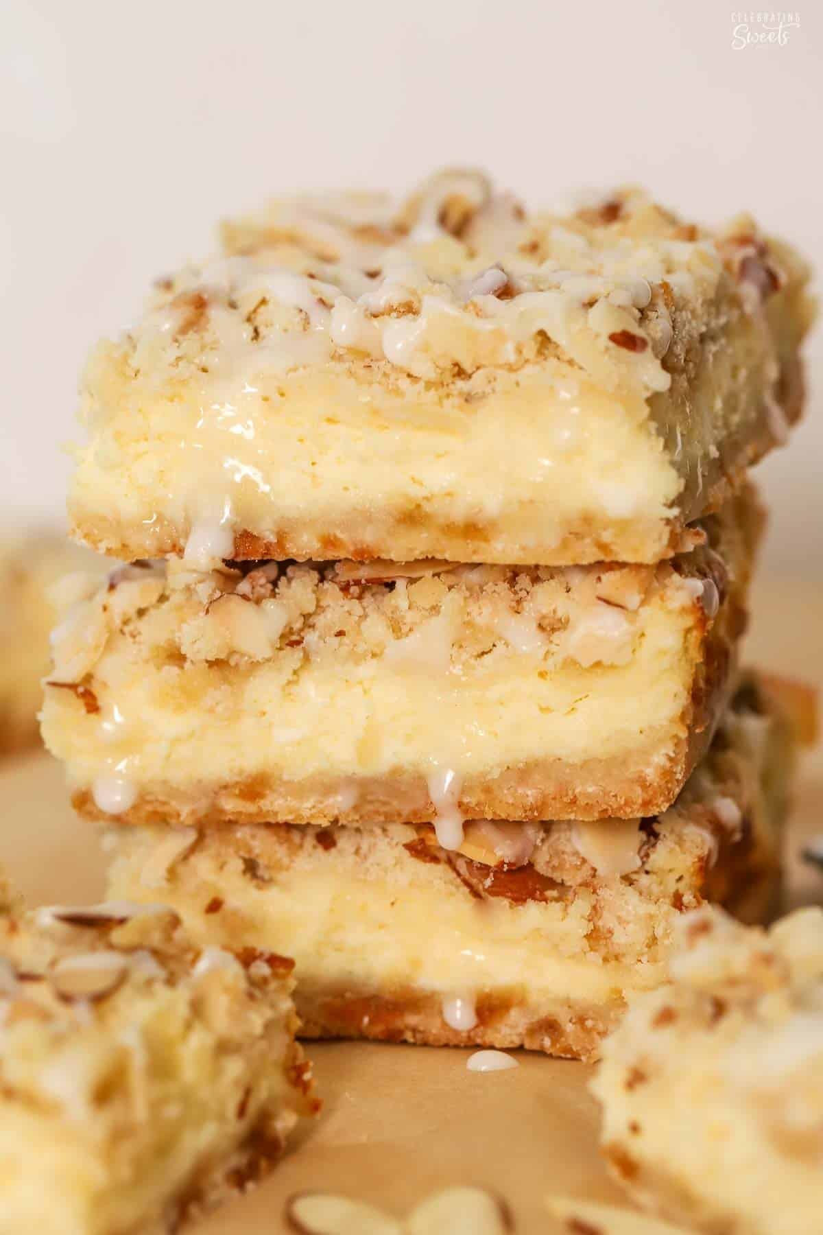 Stack of three almond cheesecake bars on parchment paper.