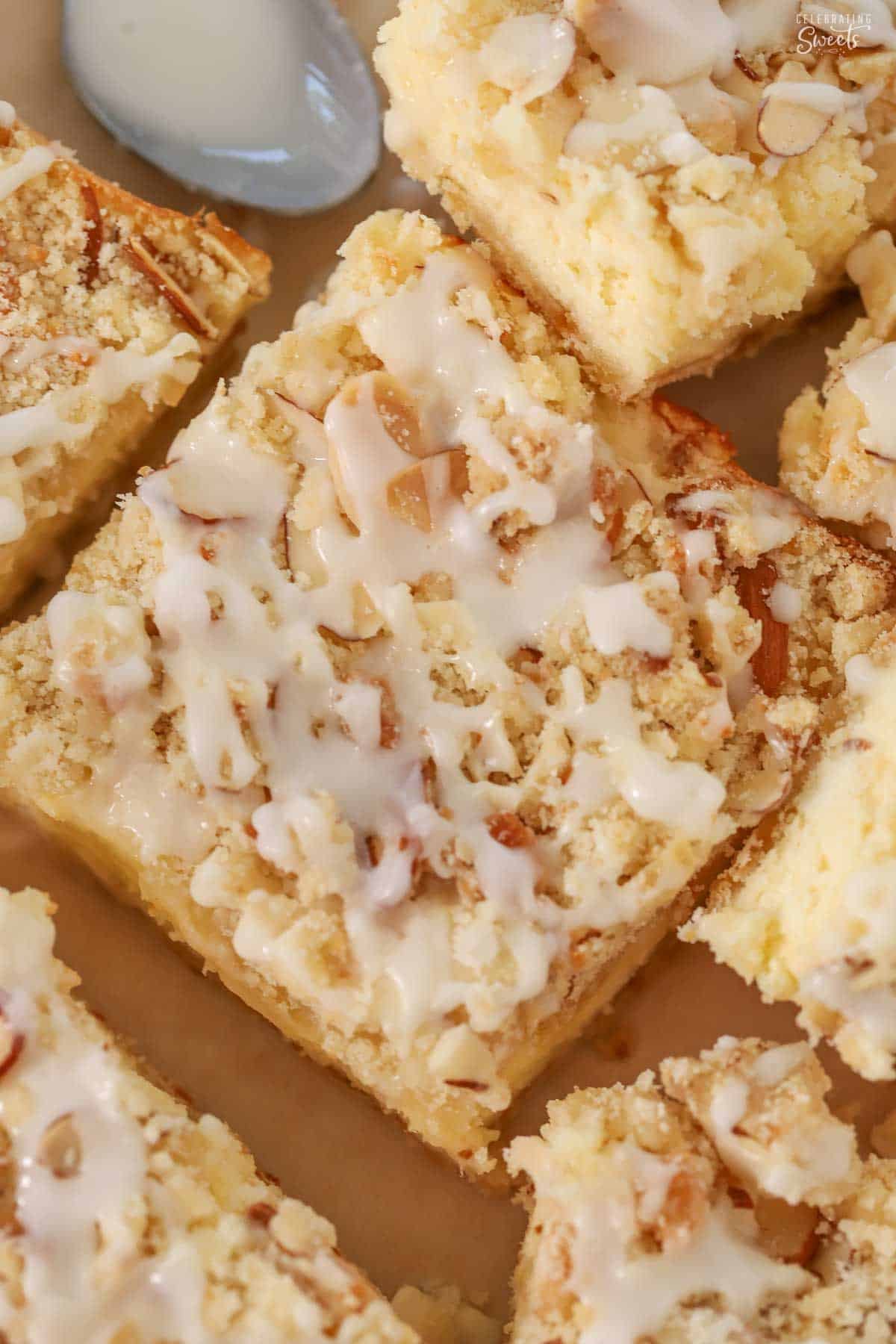 Overhead of almond cheesecake bars drizzled with icing.