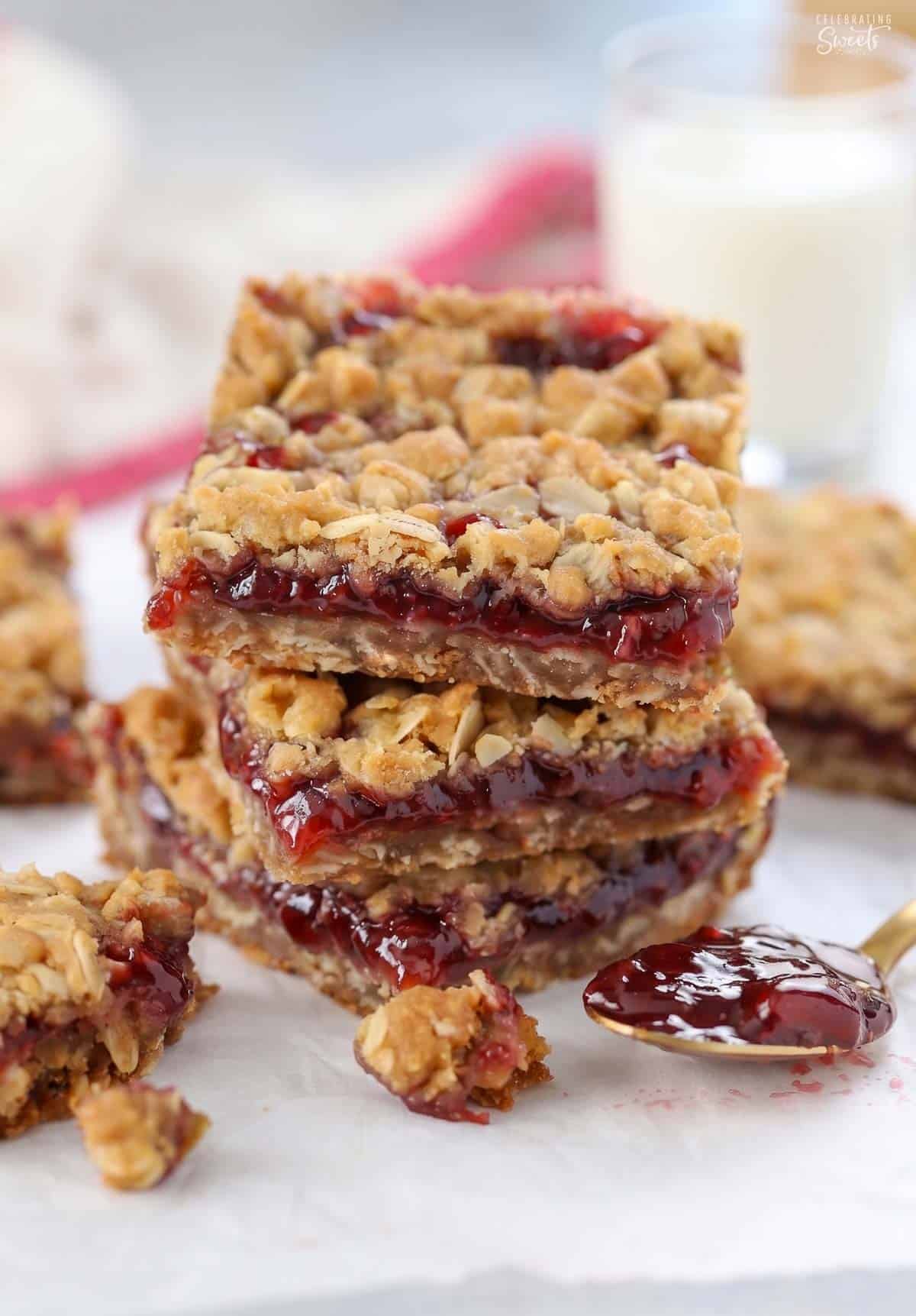 Oatmeal jam bars topped with a scoop of vanilla ice cream on a grey plate with a gold fork.