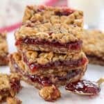 Stack of three oatmeal jam bars on parchment paper.