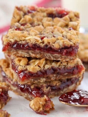 Stack of three oatmeal jam bars on parchment paper.