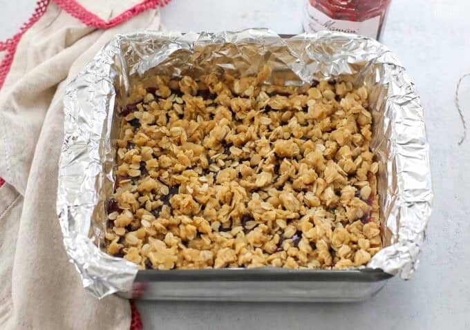 Unbaked oatmeal jam bars in a foil-lined baking dish.