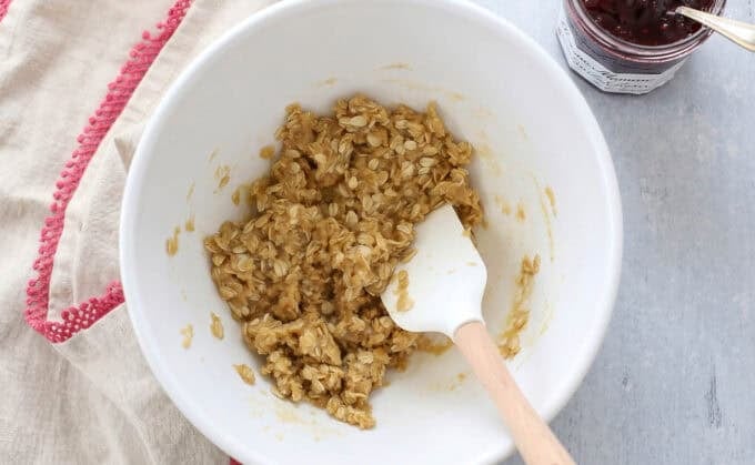 Oatmeal cookie dough in a white bowl with a white spatula.