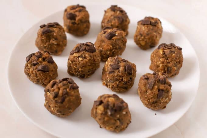 Oatmeal chocolate chip cookie dough balls on a white plate.