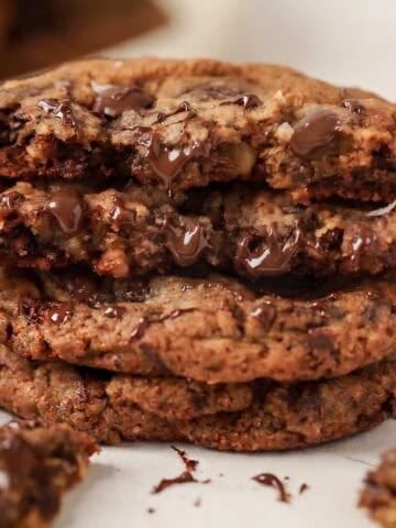 Stack of three oatmeal chocolate chip cookies with bits of melted chocolate.