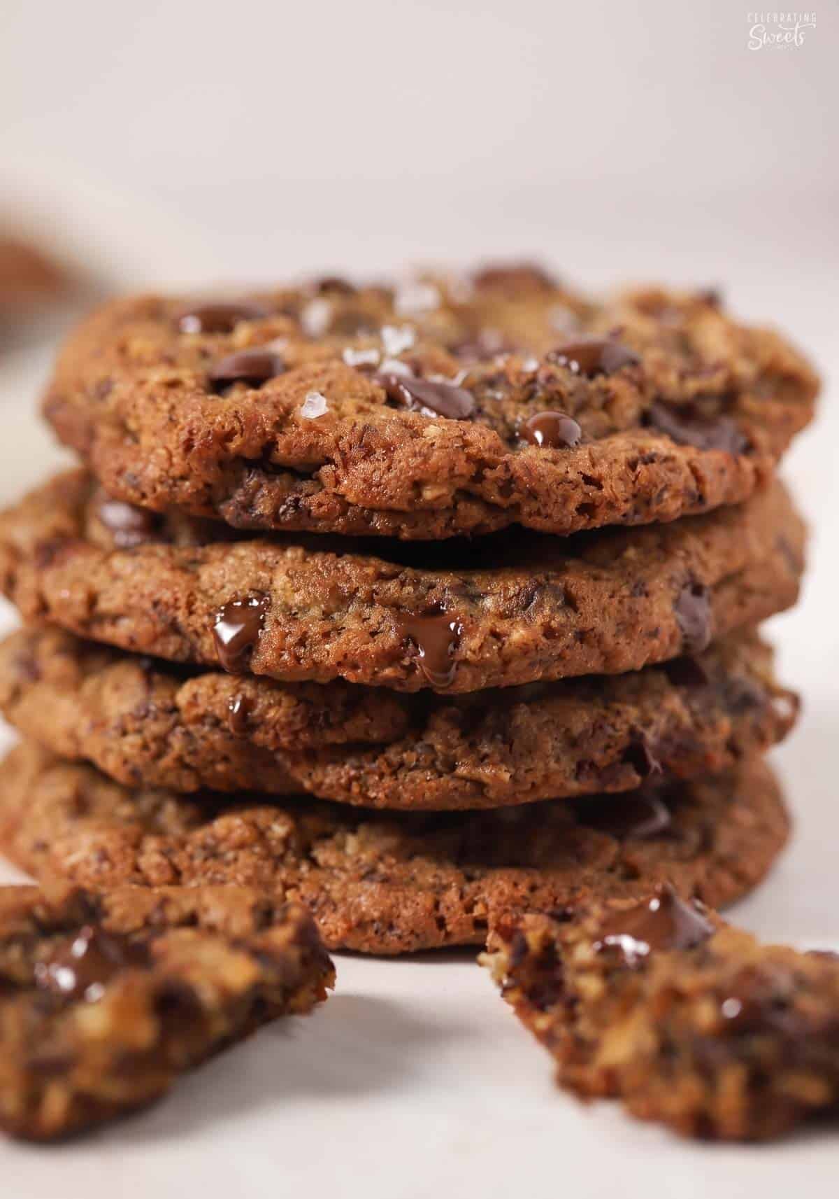 Stack of four oatmeal chocolate chip cookies on a piece of parchment paper.