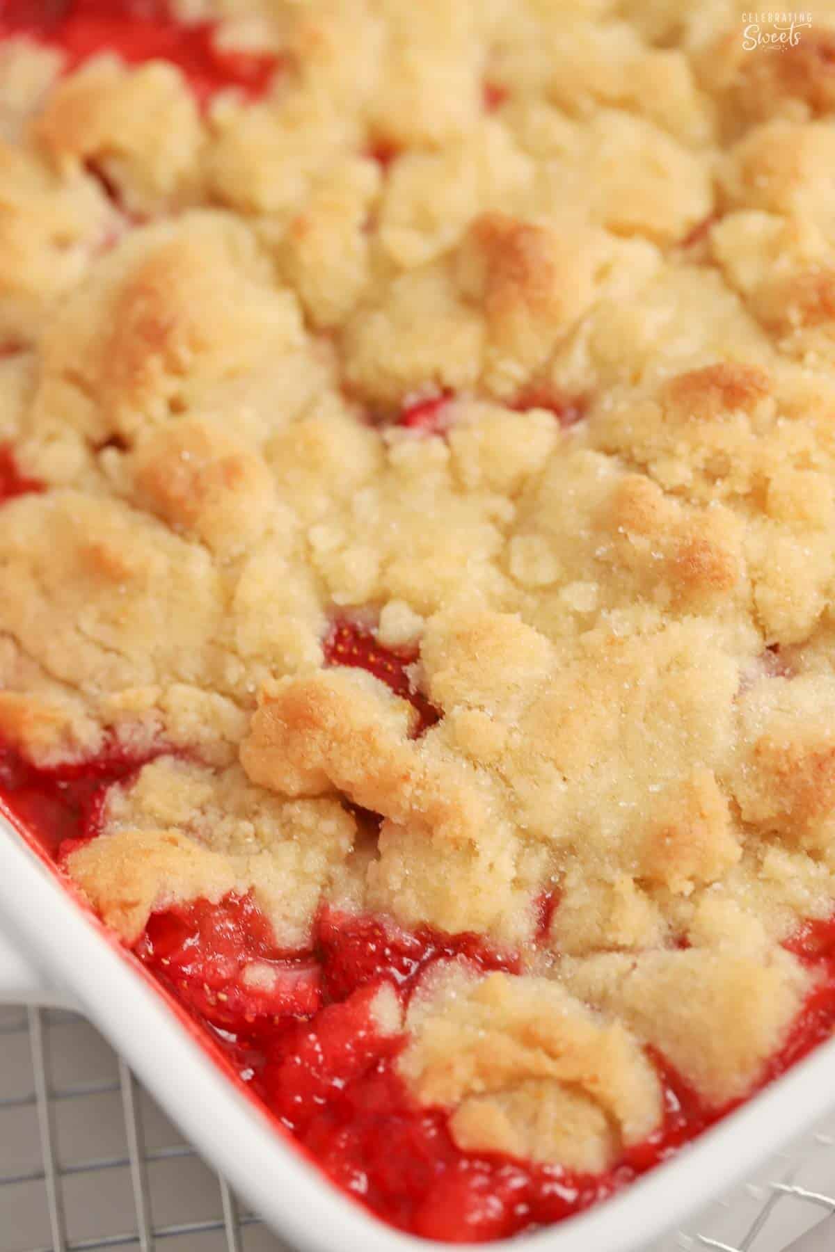 Closeup of strawberry cobbler in a white square baking dish.