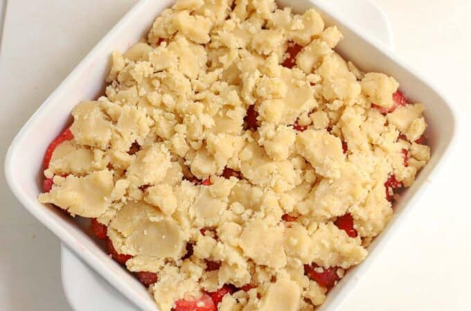 Unbaked strawberry cobbler in a white baking dish.