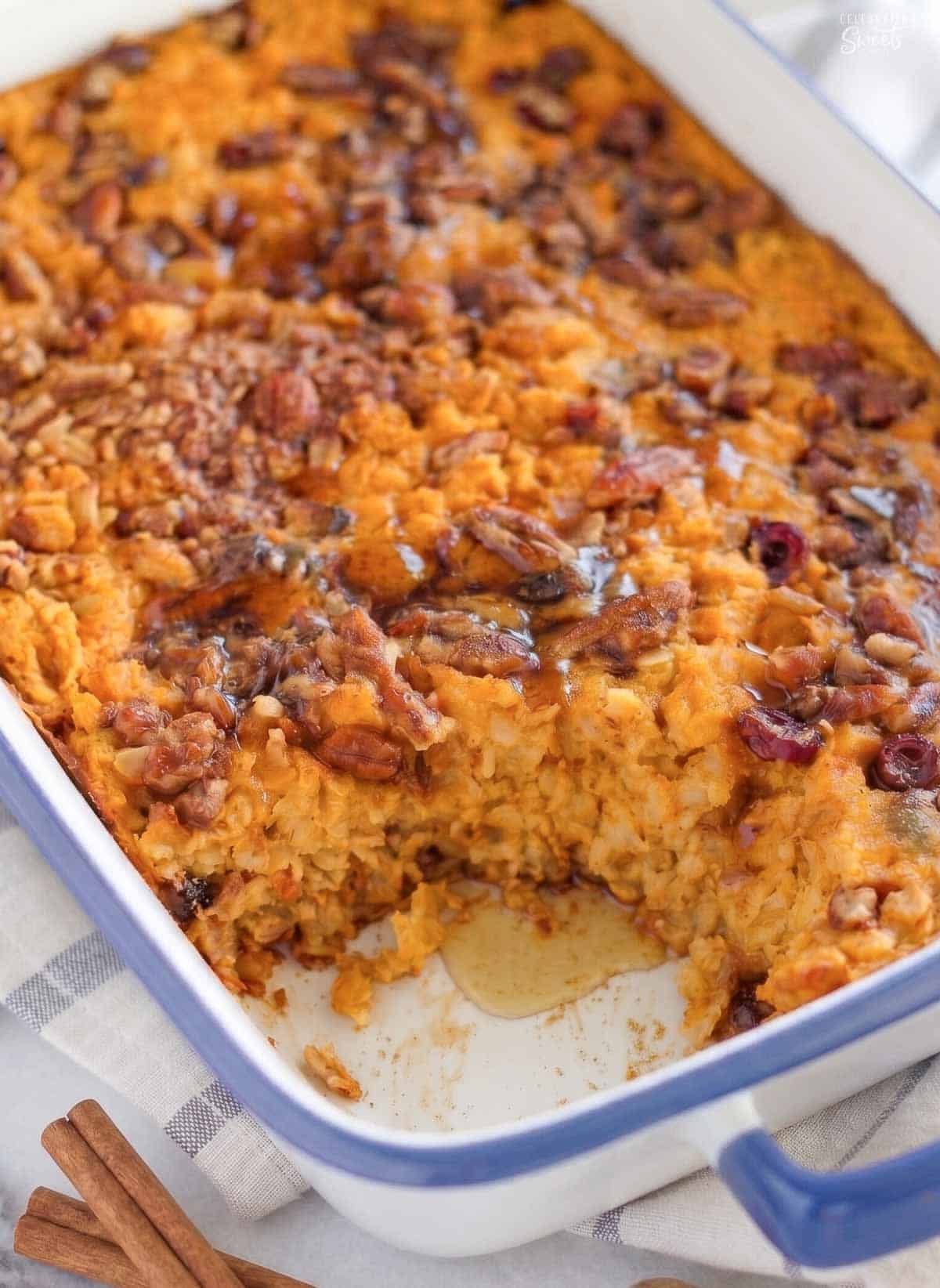 Pumpkin baked oatmeal in a blue and white baking dish next to two cinnamon sticks.