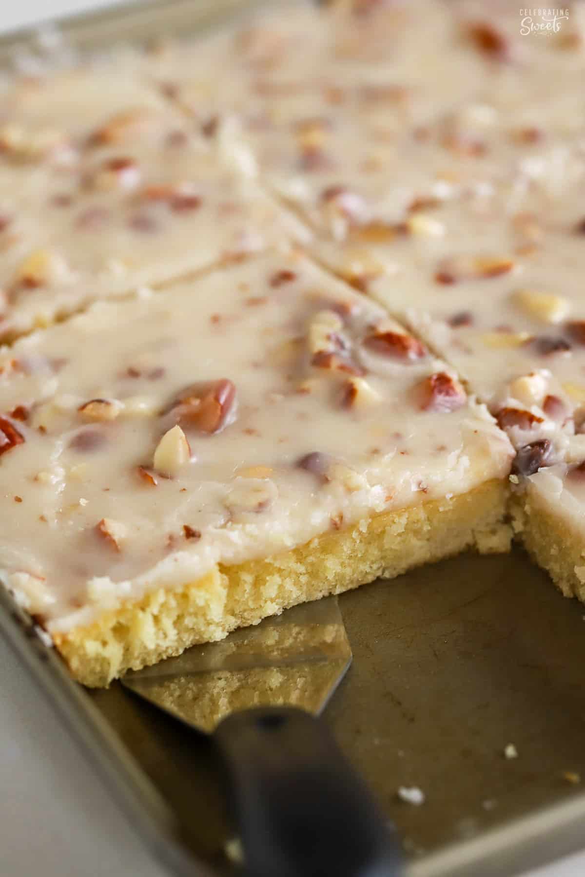 White Texas sheet cake in a shallow pan with a metal spatula.