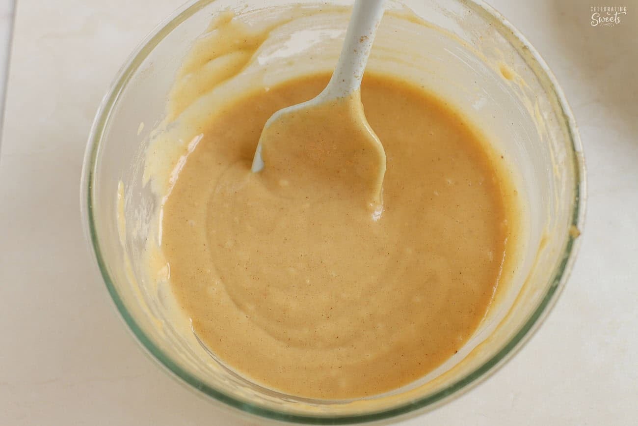 Cake batter in a glass bowl with a grey silicone spatula.