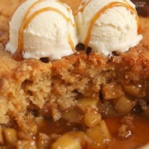 Cake on top of diced apples in caramel sauce topped with two scoops of ice cream.