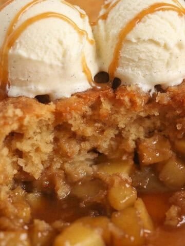 Cake on top of diced apples in caramel sauce topped with two scoops of ice cream.