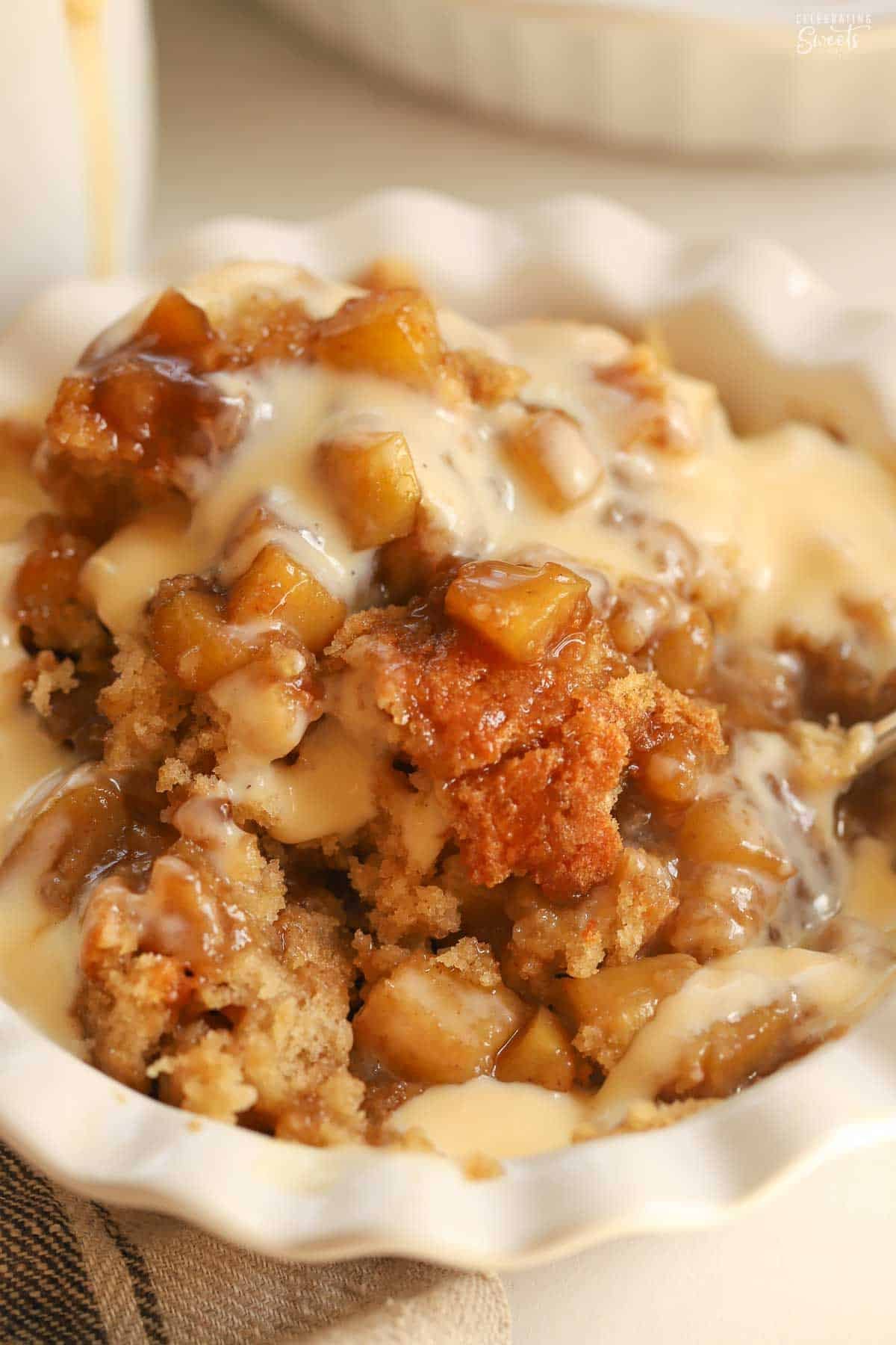 Scoops of caramel apple cake in white bowl topped with vanilla custard.
