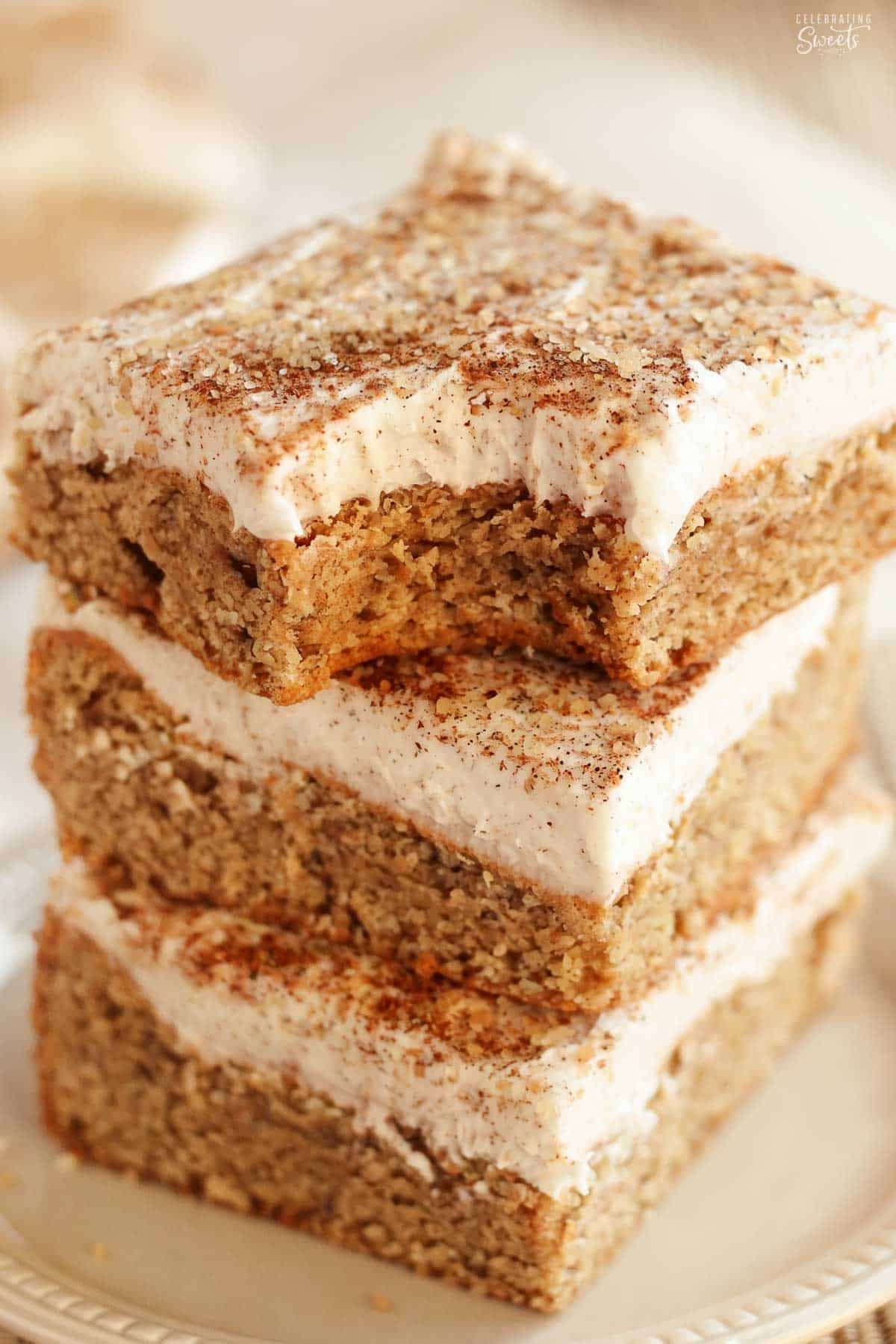 Stack of three frosted chai spice cookie bars on a beige plate.