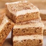 Stack of four frosted chai cookie bars on parchment paper.