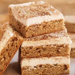 Stack of four frosted chai cookie bars on parchment paper.