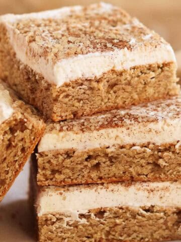 Stack of four frosted chai cookie bars on parchment paper.
