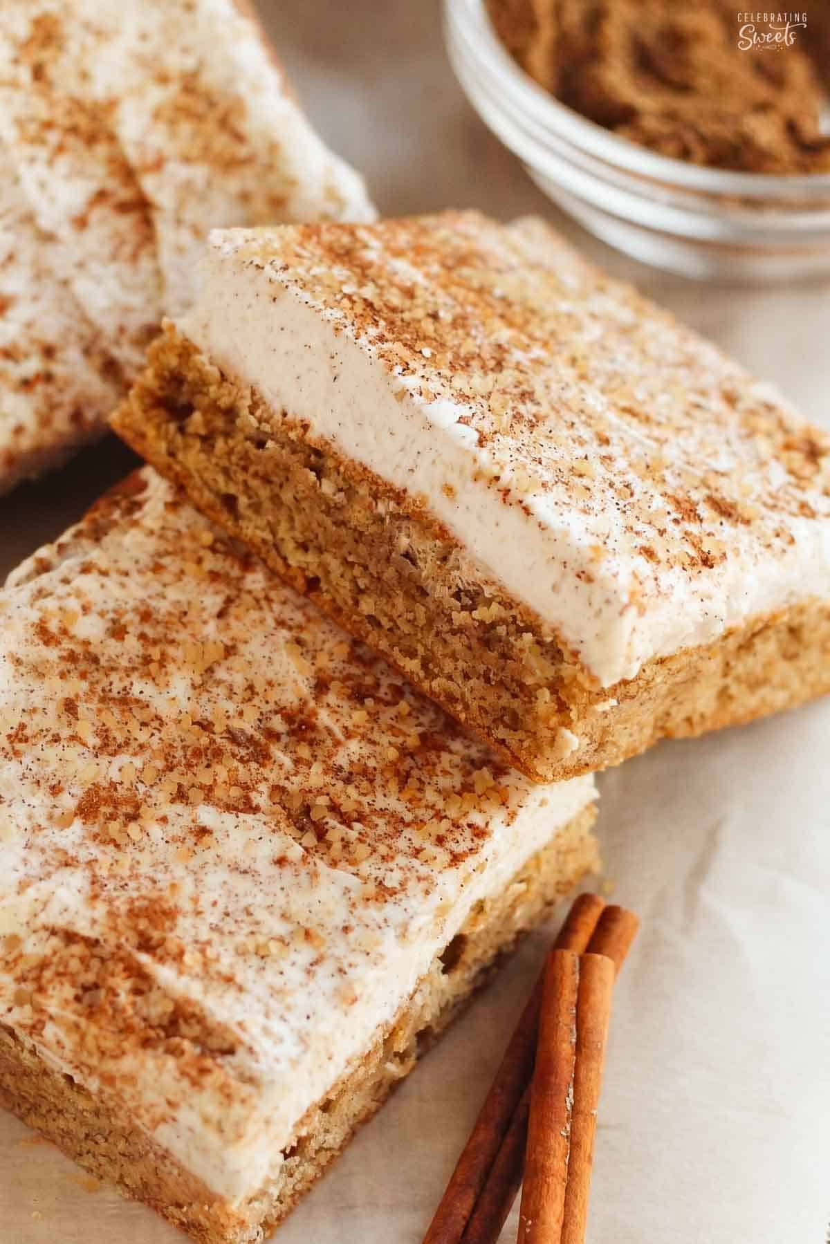 A frosted chai cookie bar leaning on another bar next to two cinnamon sticks.