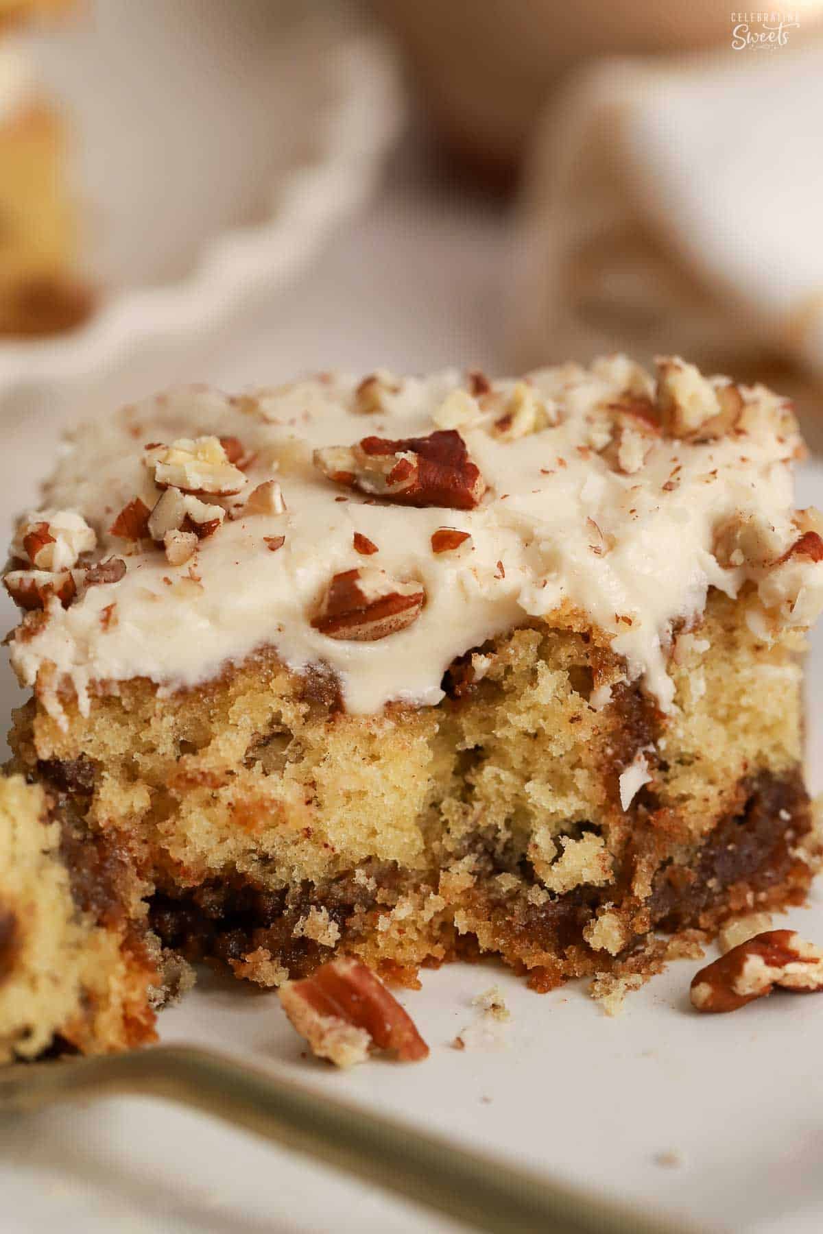 A slice of maple cinnamon swirl cake topped with pecans on a white plate.
