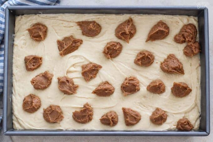 Cake batter topped with dollops of cinnamon butter in a cake pan.