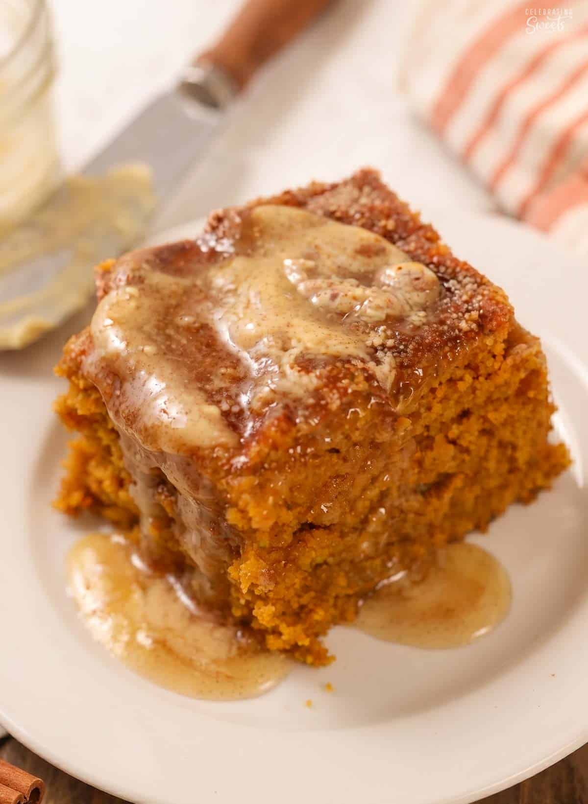 Square slice of pumpkin cake on a white plate topped with melted honey butter.