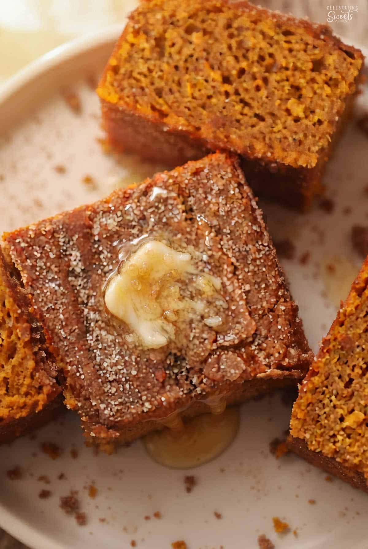 Slice of pumpkin cake on a white plate topped with cinnamon sugar and honey butter.