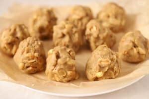 Peanut cookie dough balls on a parchment-lined plate.